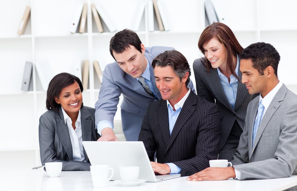 Multi-cultural business team looking at a laptop in the office