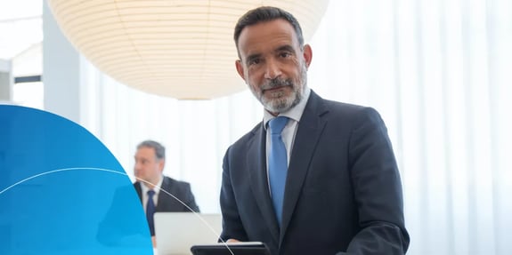 A man in a suit sitting in an office looking at the camera