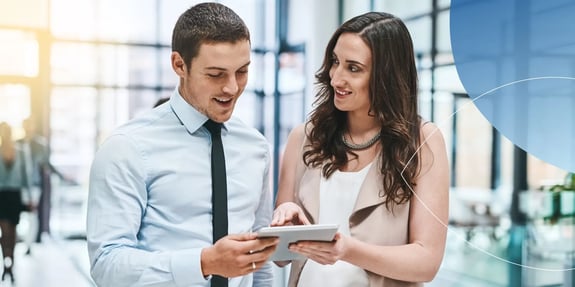 One male and one female employee standing together looking into tablet 
