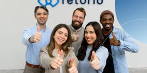 Five employees standing together with their thumbs up