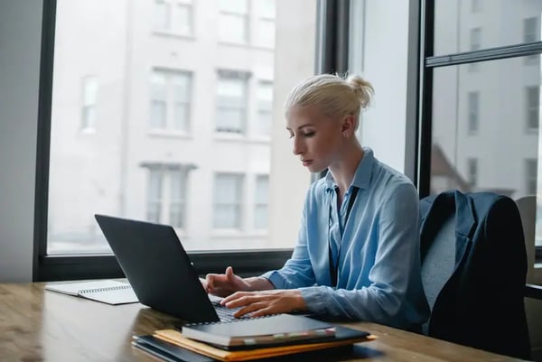 Woman sitting at desk typing on laptop 