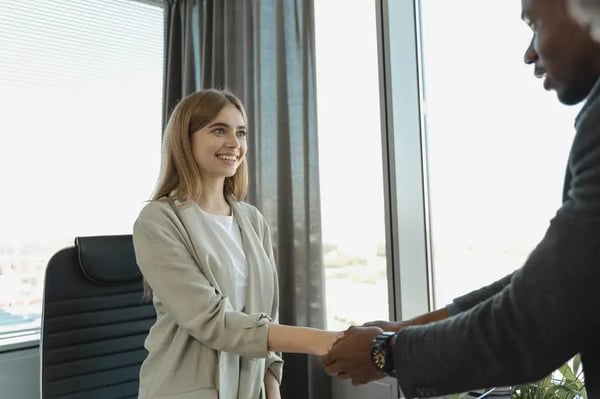 Female employee shaking hands with male employee and smiling
