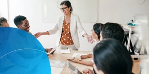 Woman standing behind meeting table and smiling at her employees
