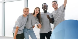 three male and one female wearing grey t-shirts with their arms around each other smiling