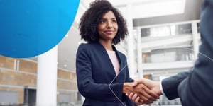 Woman in suit shaking hands with another hand 