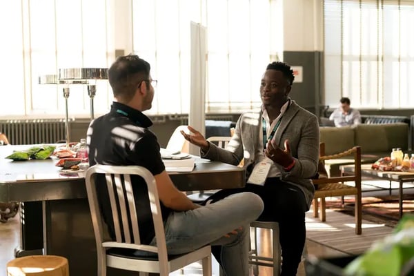 Two male employees sitting at desk discussing