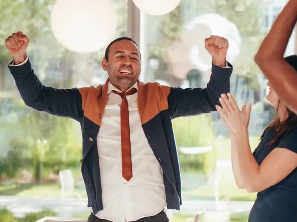 Man smiling and holding his arms up with hands in fist showing excitement