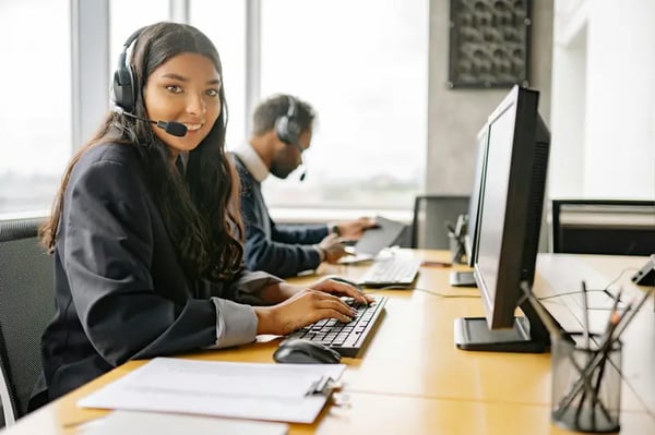 Woman looking at the camera and getting customer service training at the same time while wearing headset