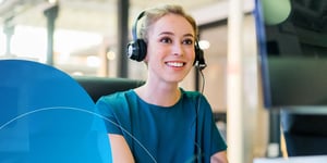 Women wearing headset smiling at the computer screen