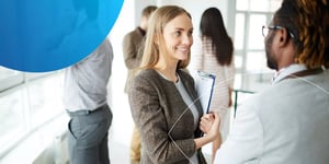 Woman holding a clipboard and smiling at a man in front of her 