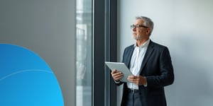 A head of sales enablement reviewing a budget spreadsheet next to a laptop showing an AI coaching dashboard