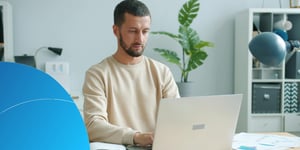 Mann arbeitet konzentriert am Laptop in einem hellen Büro
