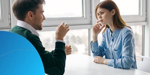 Ein Mann und eine Frau im Gespräch an einem Tisch am Fenster