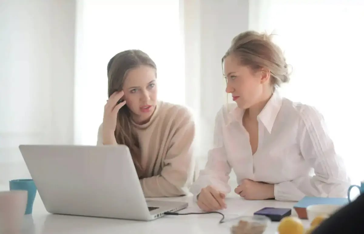 behavioral intelligence versus emotional intelligence with two women sitting at office desk discussing together 