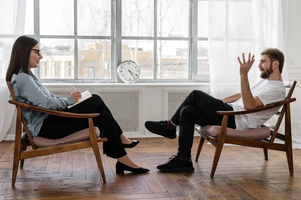 A man and a woman sitting on chairs opposite each other talking