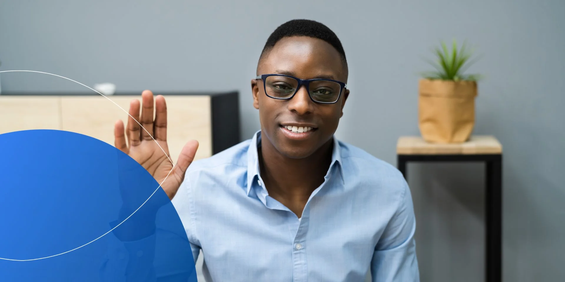 Man wearing blue t-shirt waving into camera 