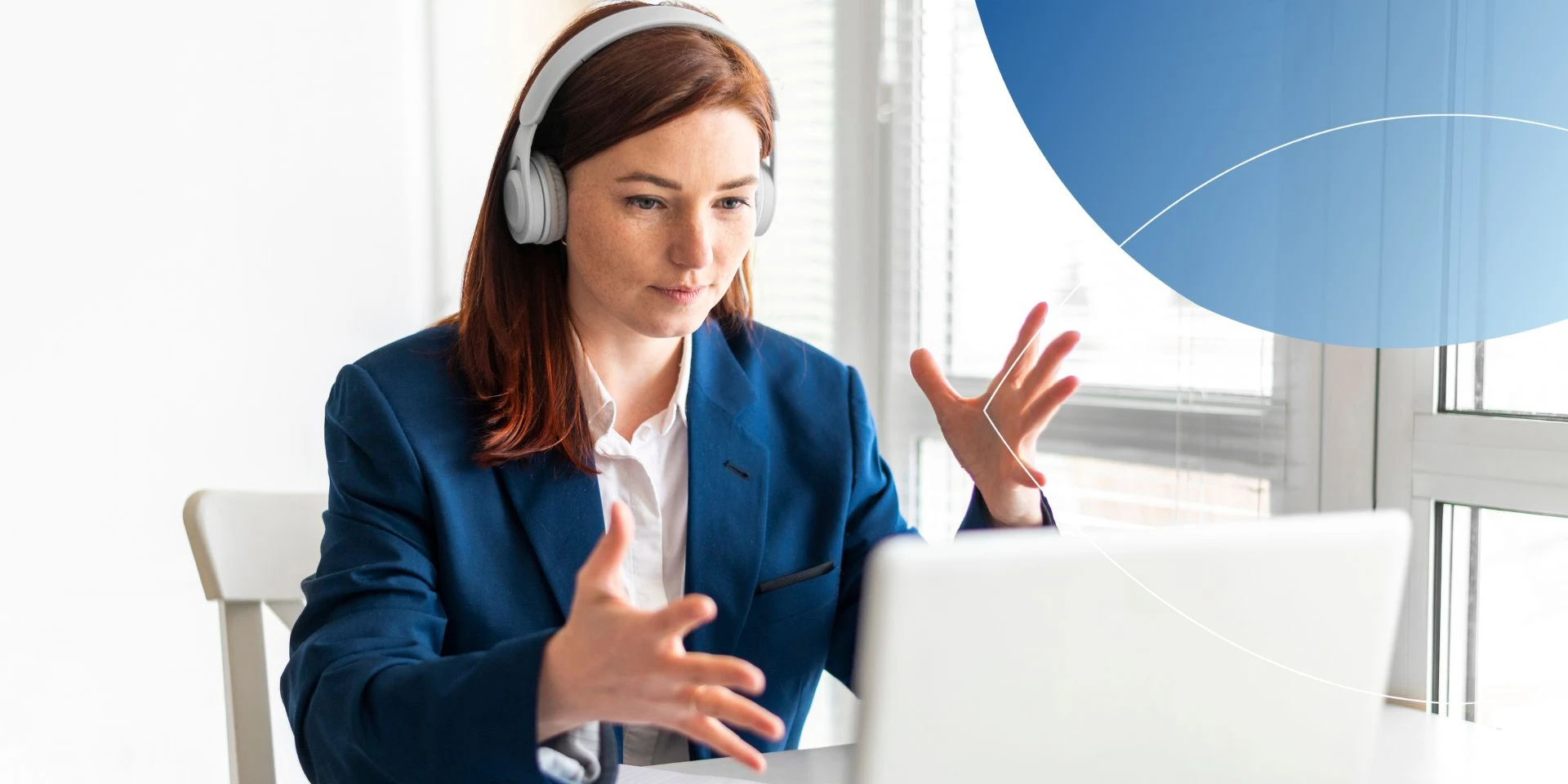 woman wearing blue suit and headphones talking to laptop