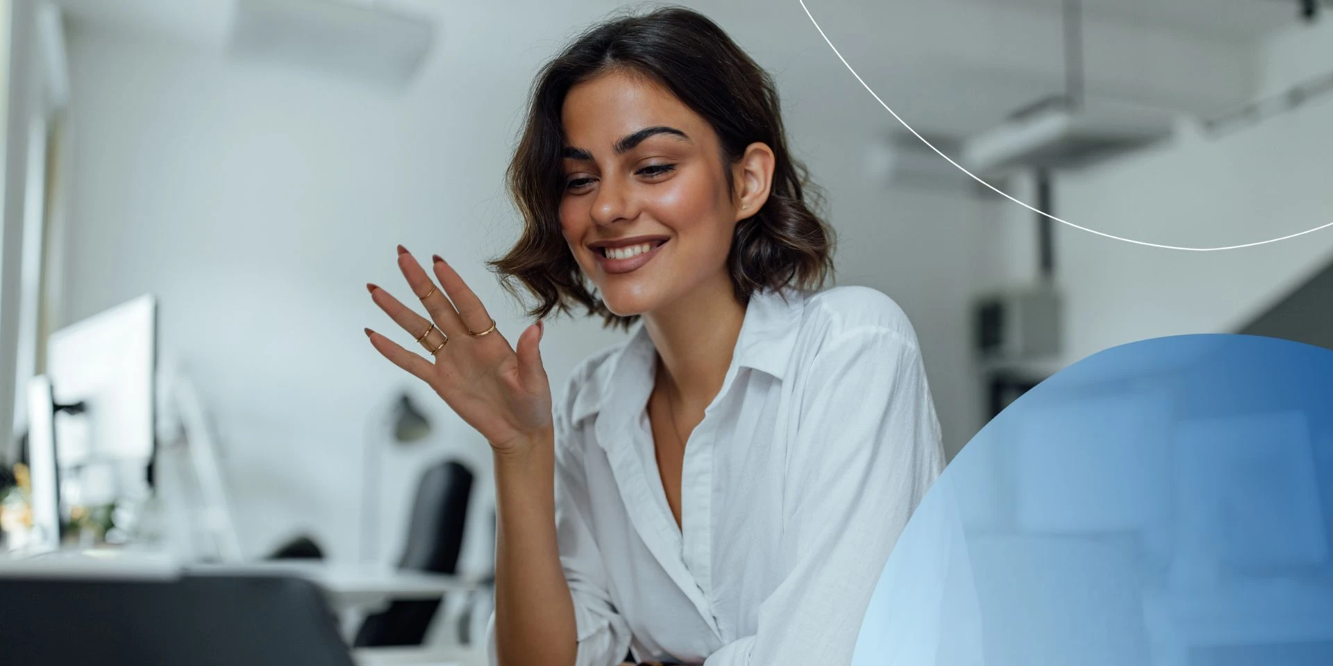 Woman sitting at desk waving to her laptop