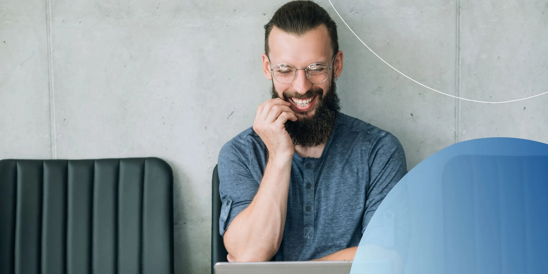 man laughing at his laptop  with hand close to mouth