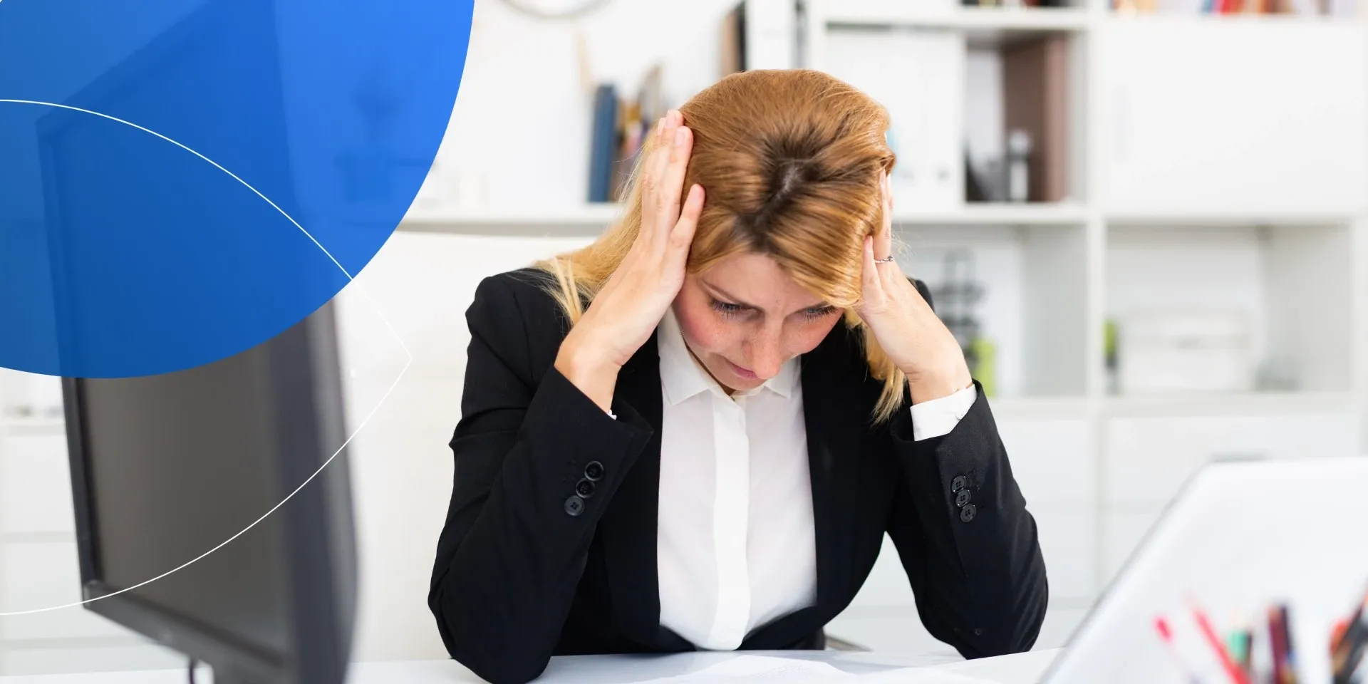 woman looking down at her desk stressed with her hands by her head 