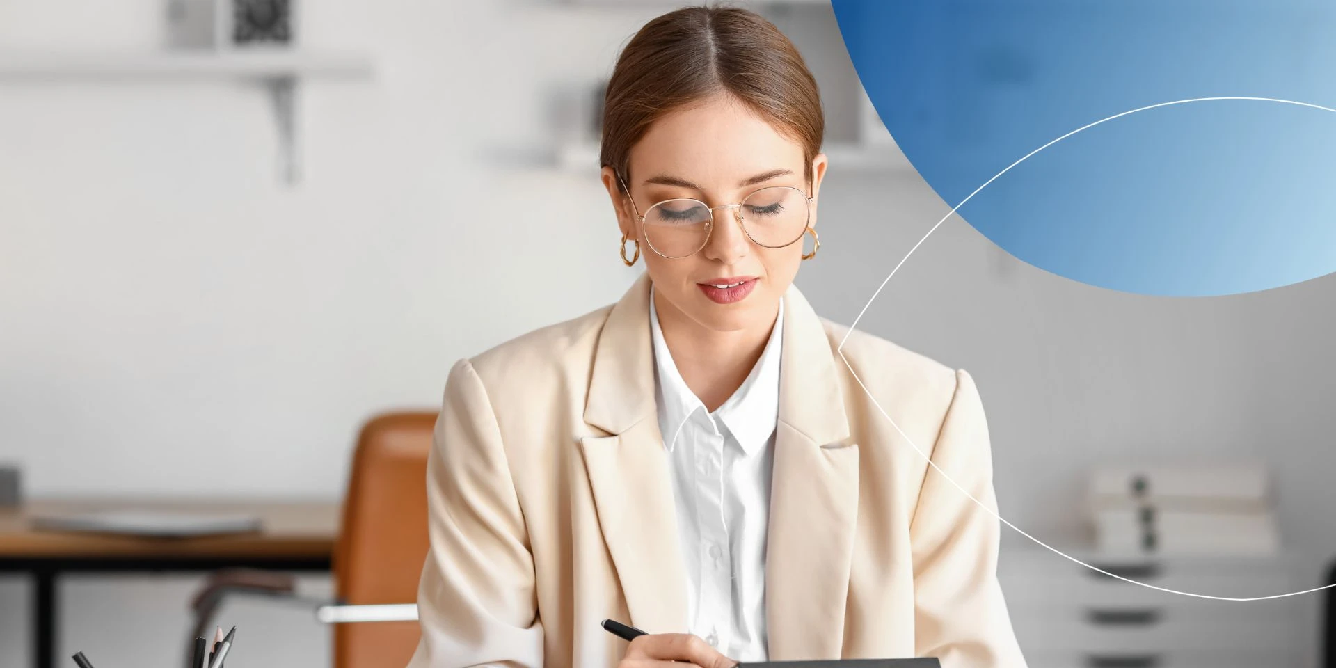 woman in beige blazer looking at her tablet and writing something on it 