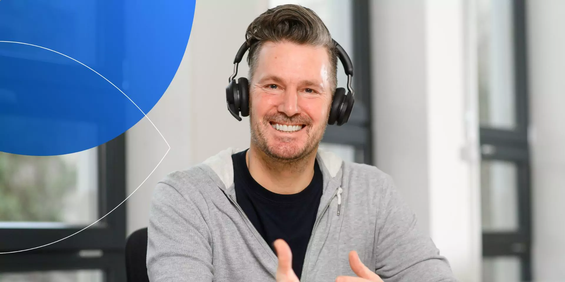 man wearing headphones smiling to camera with hand gesture