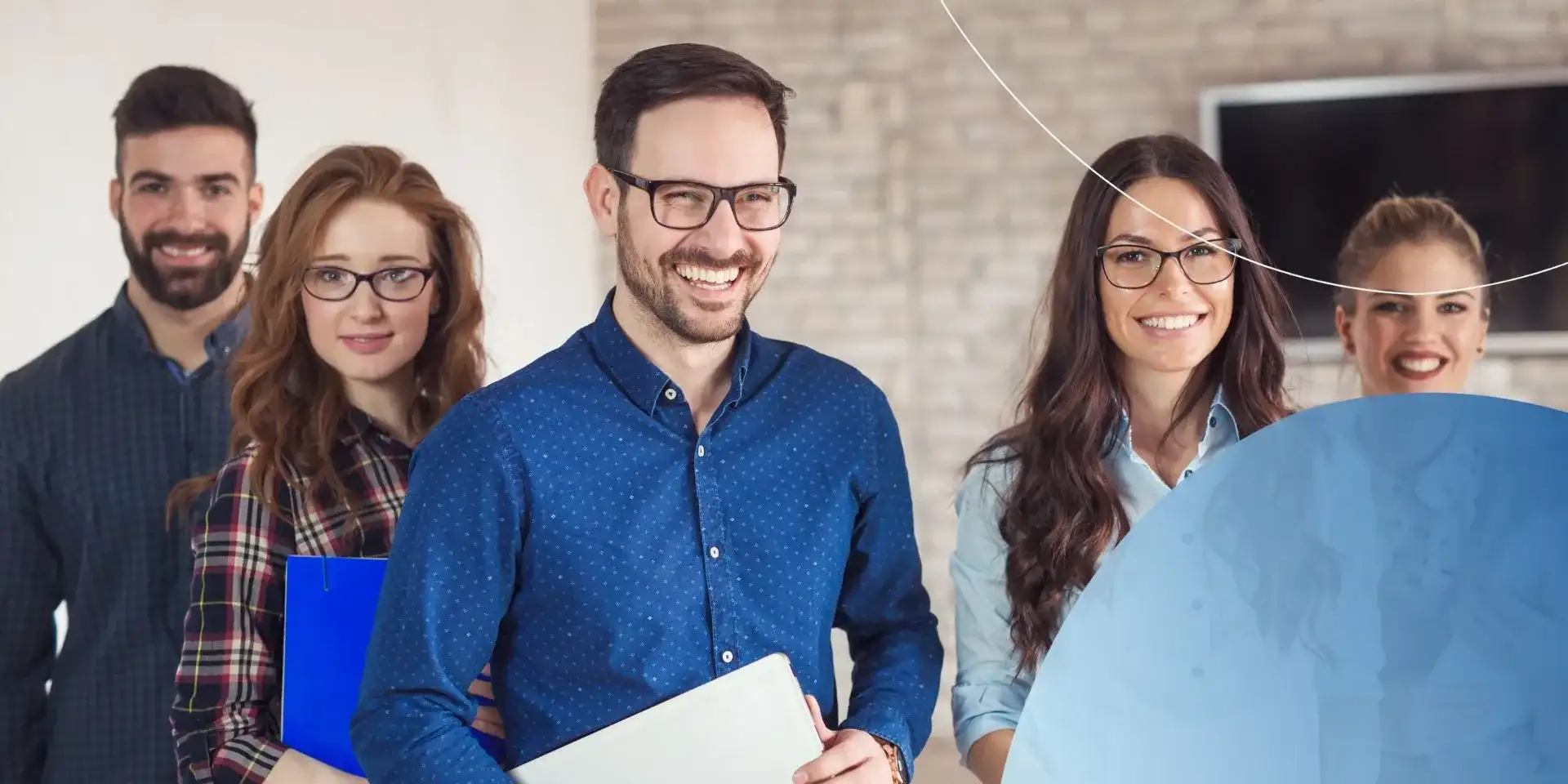 Man wearing glasses smiling with other people standing around him smiling 